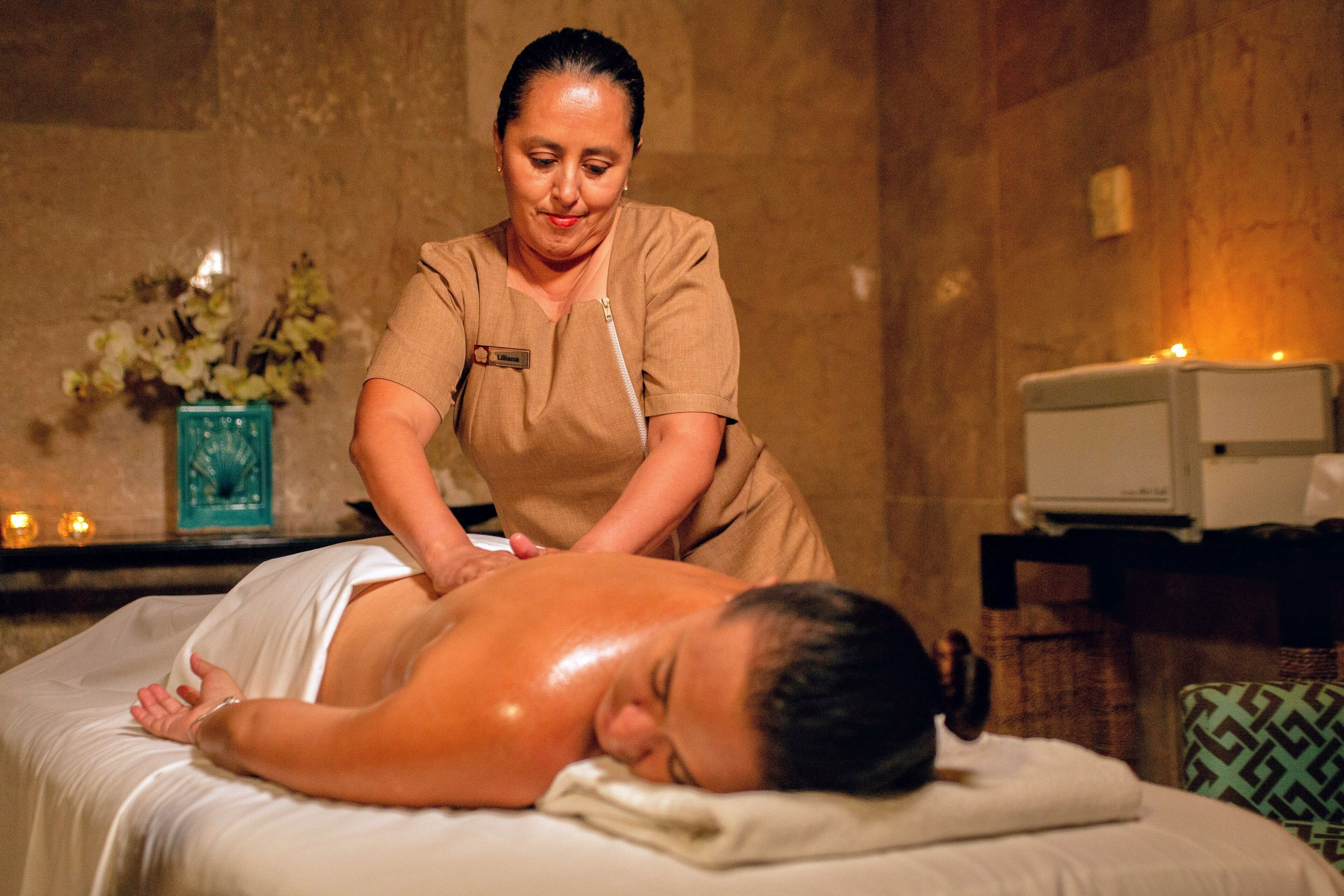 Een massagebehandeling in een wellness omgeving, met een massagetafel, een therapeut en een kleine televisie op een bijzettafeltje.