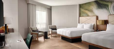 A hotel room with two beds, a desk, a chair, a small table, and a large abstract painting on the wall.