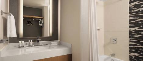 A modern bathroom with a white sink, mirror, and bathtub.