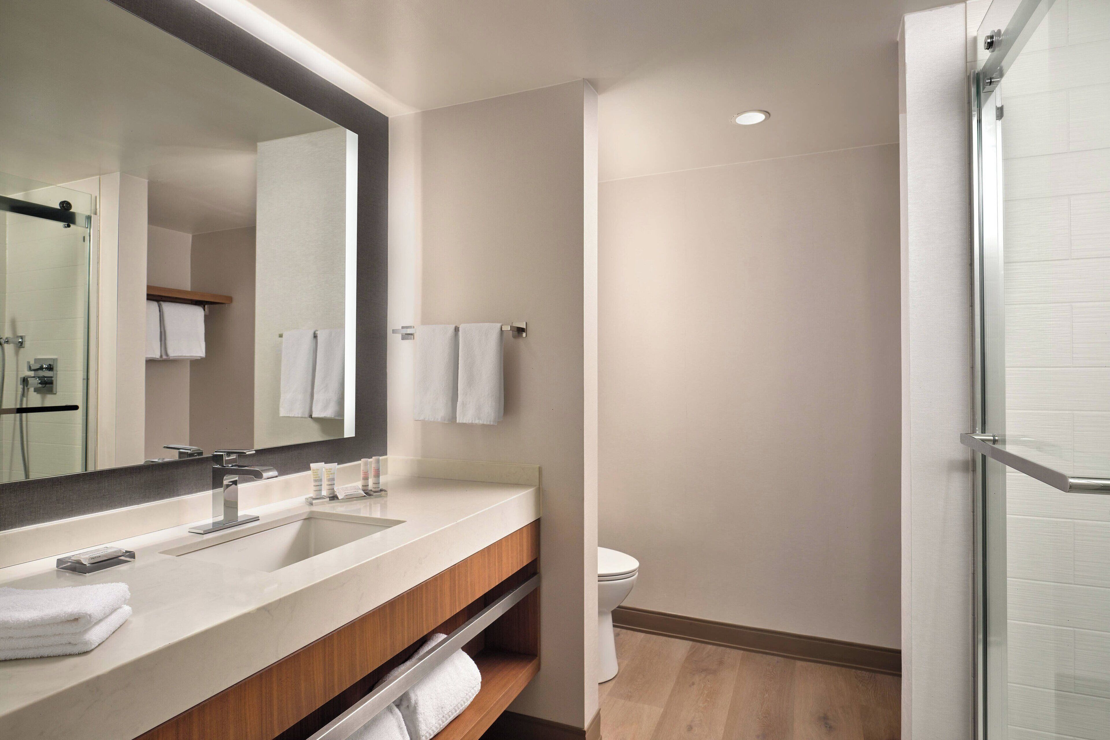 Un baño moderno con un espejo grande, un lavabo y un inodoro.