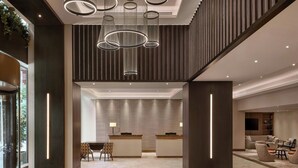 A modern hotel lobby with a reception desk, seating area, and a staircase. - London Marriott Hotel Marble Arch (London)
