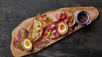 Un tagliere di legno con salumi assortiti, sottaceti e fette di pane.