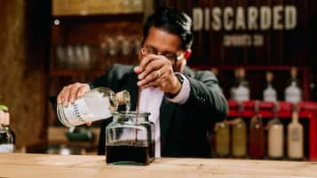 A person pouring liquid from a bottle into a glass jar.