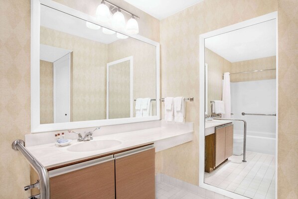 Un baño moderno con un espejo grande, un lavamanos y una zona de ducha.