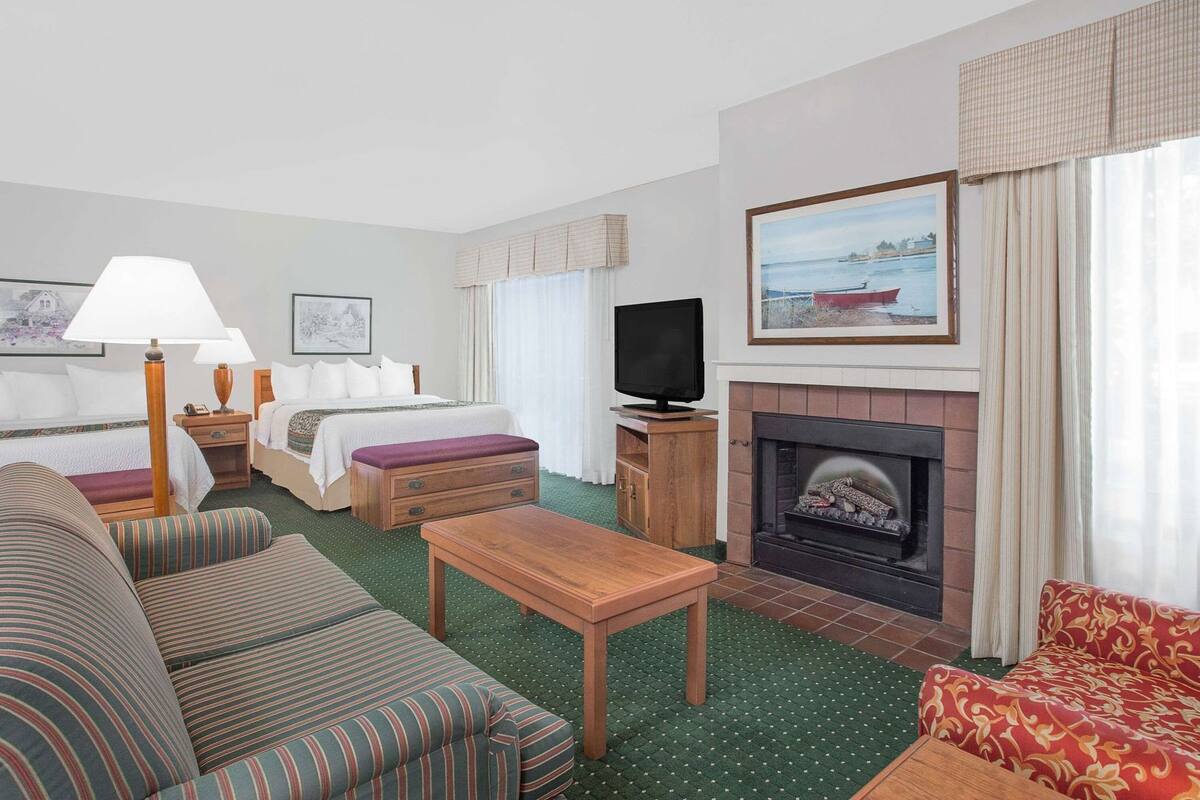A hotel room with a bed, a television, a fireplace, a sofa, and a dining table.