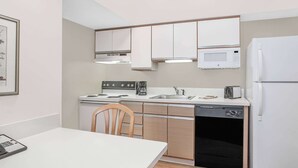 A compact kitchen with white cabinets, a microwave, a stove, a sink, and a dishwasher.
