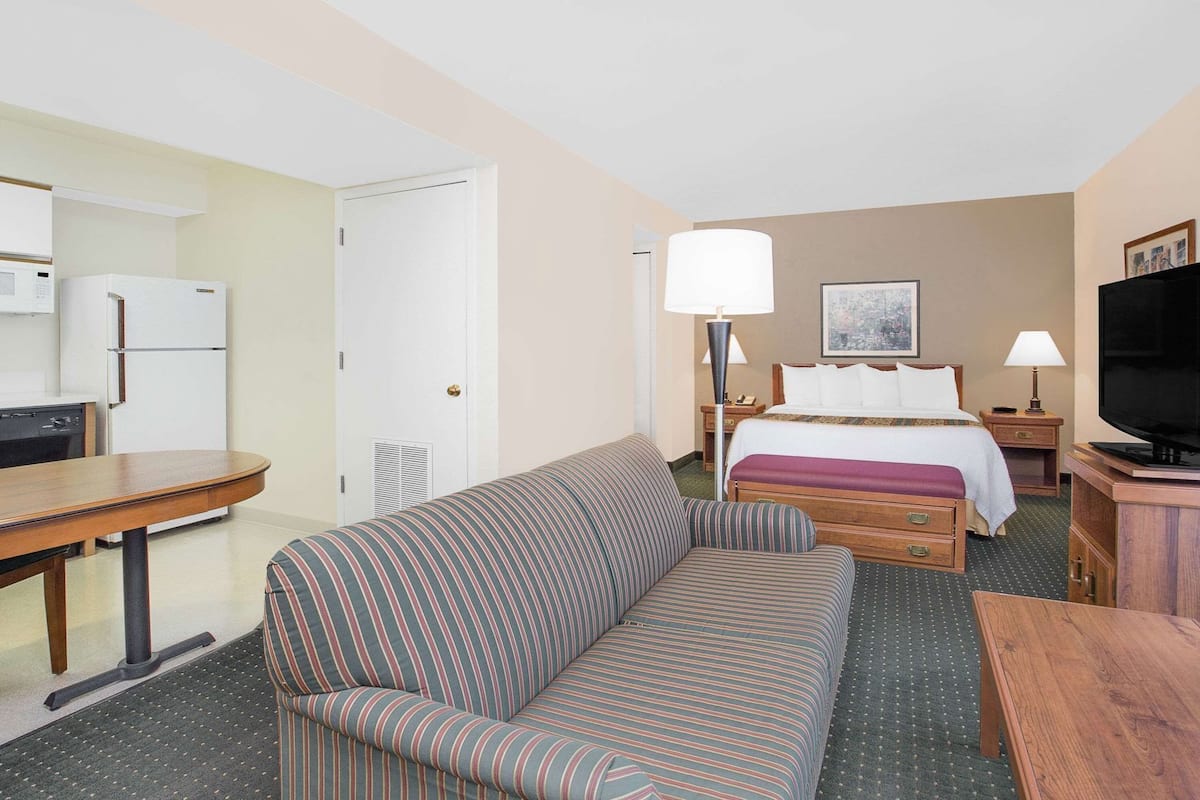 A hotel room with a bed, a sofa, a desk, a television, and a microwave.