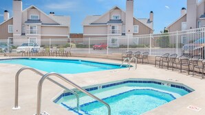 A swimming pool with a metal ladder, surrounded by a white fence.