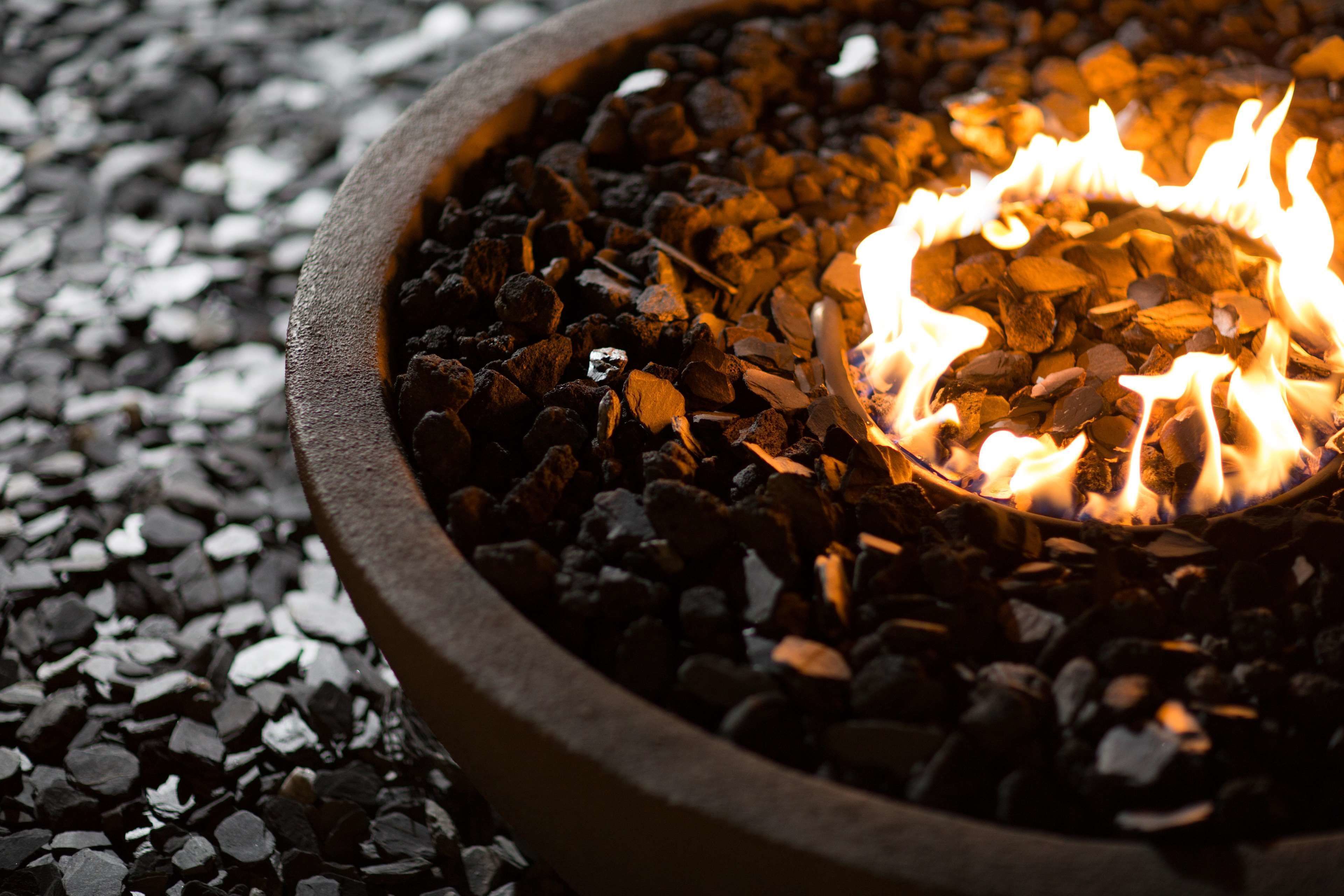 A close-up of a fire pit with burning wood surrounded by gravel.