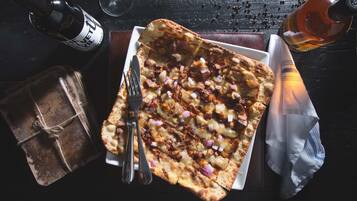 Una pizza con ingredientes, una botella, un vaso y un regalo envuelto sobre una mesa.