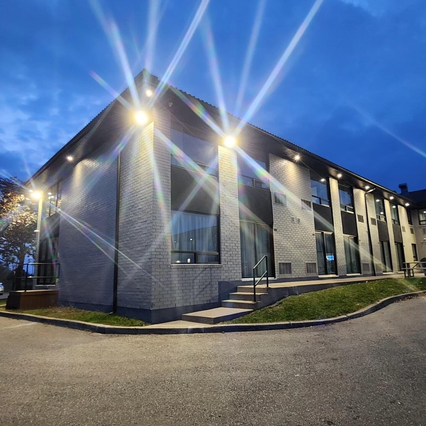 A modern building with a brick facade, large windows, and a well-lit entrance.