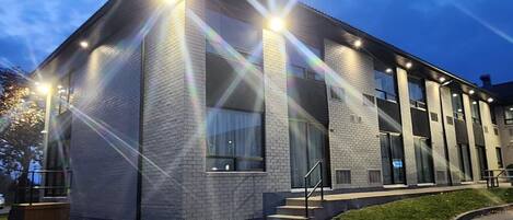Un bâtiment moderne avec une façade en briques, de grandes fenêtres et une entrée bien éclairée.