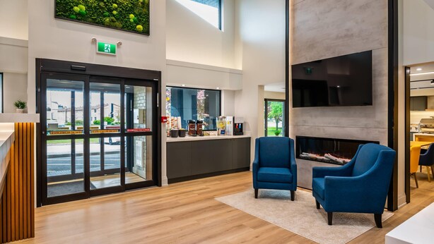 A modern lobby with a reception desk, a fireplace, and a seating area with blue chairs. - Comfort Inn Guelph (Guelph)