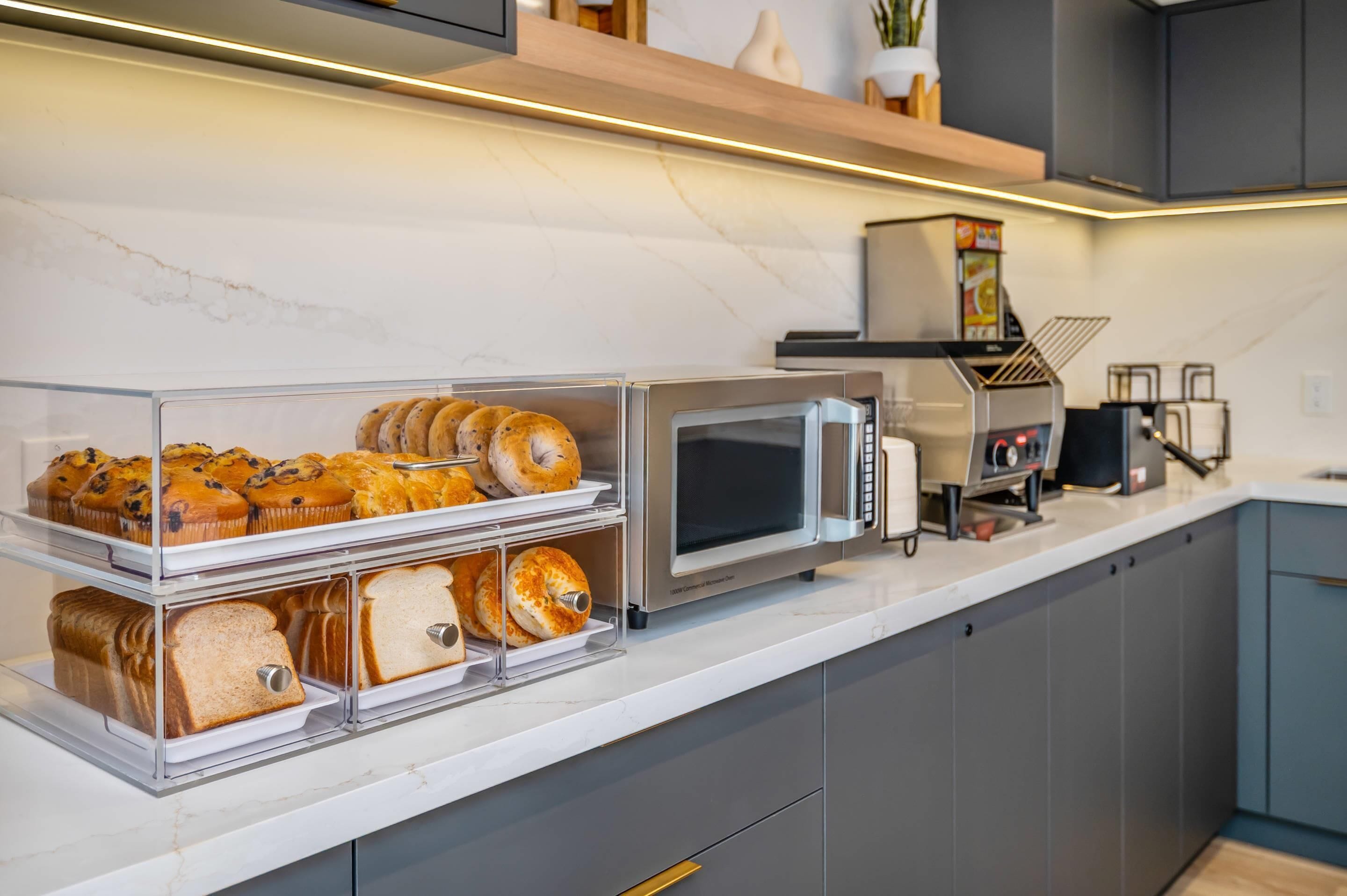 Een keuken met een broodvitrine, een magnetron en een broodrooster.