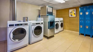 A laundry facility with multiple washing machines, a dryer, and blue lockers.