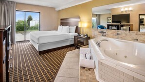 A hotel room with a large bed, a separate sofa, a bathroom with a bathtub, and a TV in the corner. - Comfort Inn Guelph (Guelph)