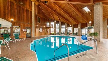 Una piscina interior con revestimiento de madera, sillones de descanso verdes y un cartel que dice 'NO DIVING'.
