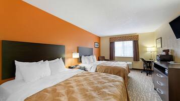 A hotel room with two beds, a desk, a chair, a dresser, and a television.