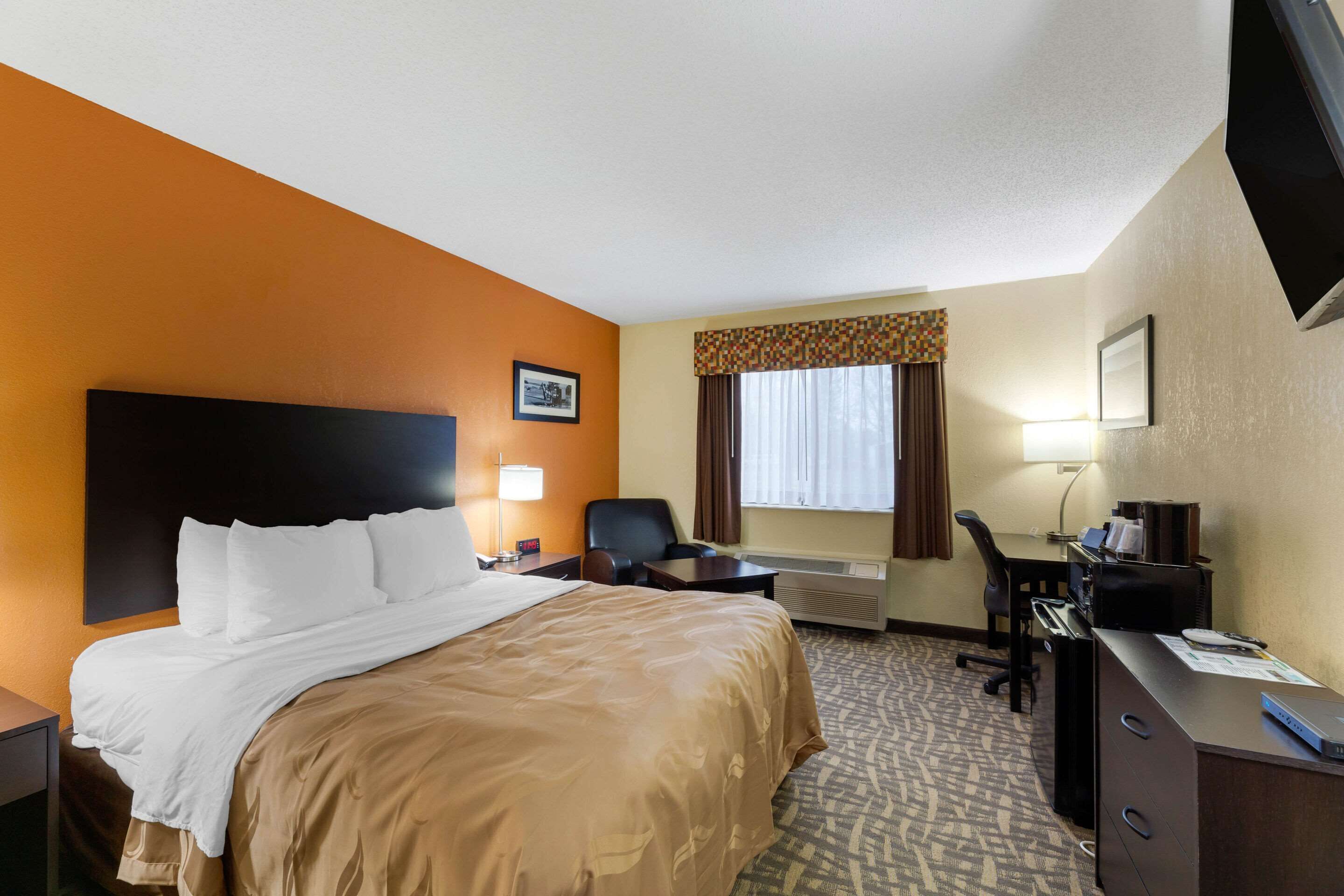 Une chambre d’hôtel équipée d’un lit, d’un bureau, d’une chaise et d’un téléviseur.