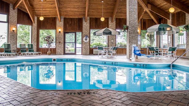 An indoor swimming pool with clear water, wooden beams, and seating areas. - Quality Inn Wooster (Wooster)