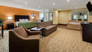 A hotel room with a bed, two sofas, a desk, and a mirror. - Quality Inn Wooster (Wooster)