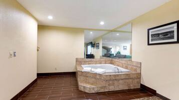 Une salle de bain moderne avec une grande baignoire, un miroir et un tapis à motifs.