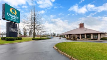 Quality Inn by Choice Hotels features a traditional building with a pitched roof and a brick facade, surrounded by a well-maintained lawn and parking area.
