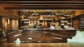Um bar moderno com balcão de madeira e prateleiras cheias de garrafas.