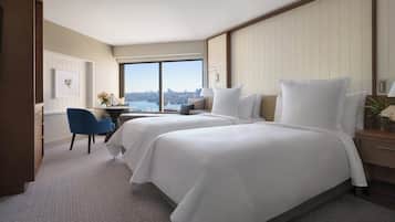 A hotel room with two beds, a desk, and a view of the city.