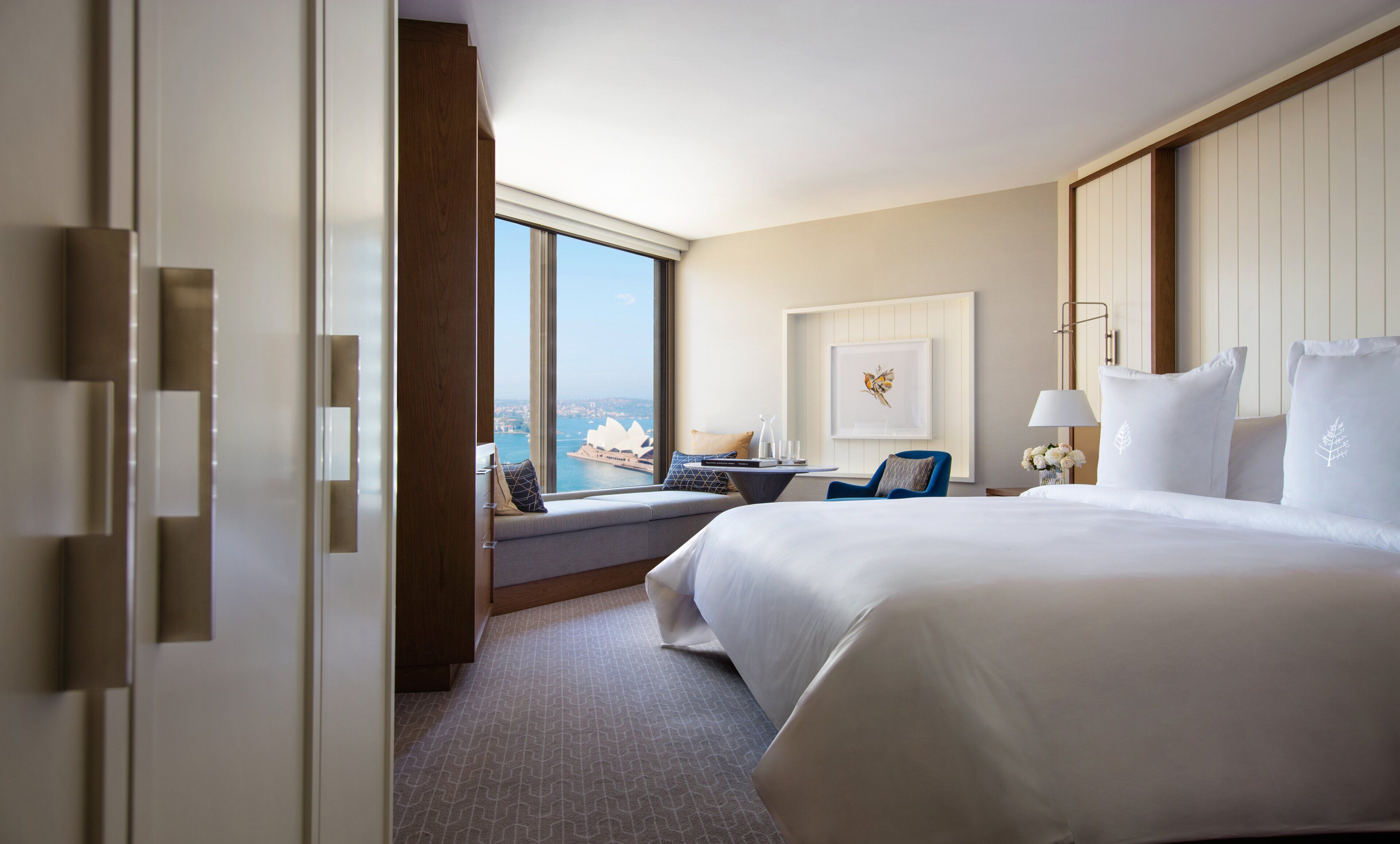 Habitación de hotel con una cama grande, zona de estar y vistas a la ciudad, además de cortinas.