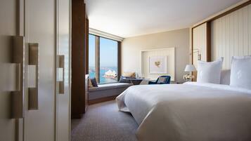Habitación de hotel con una cama grande, zona de estar y vistas a la ciudad, además de cortinas.