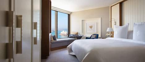 A hotel room with a large bed, a seating area with a view of the city, and a window with curtains.