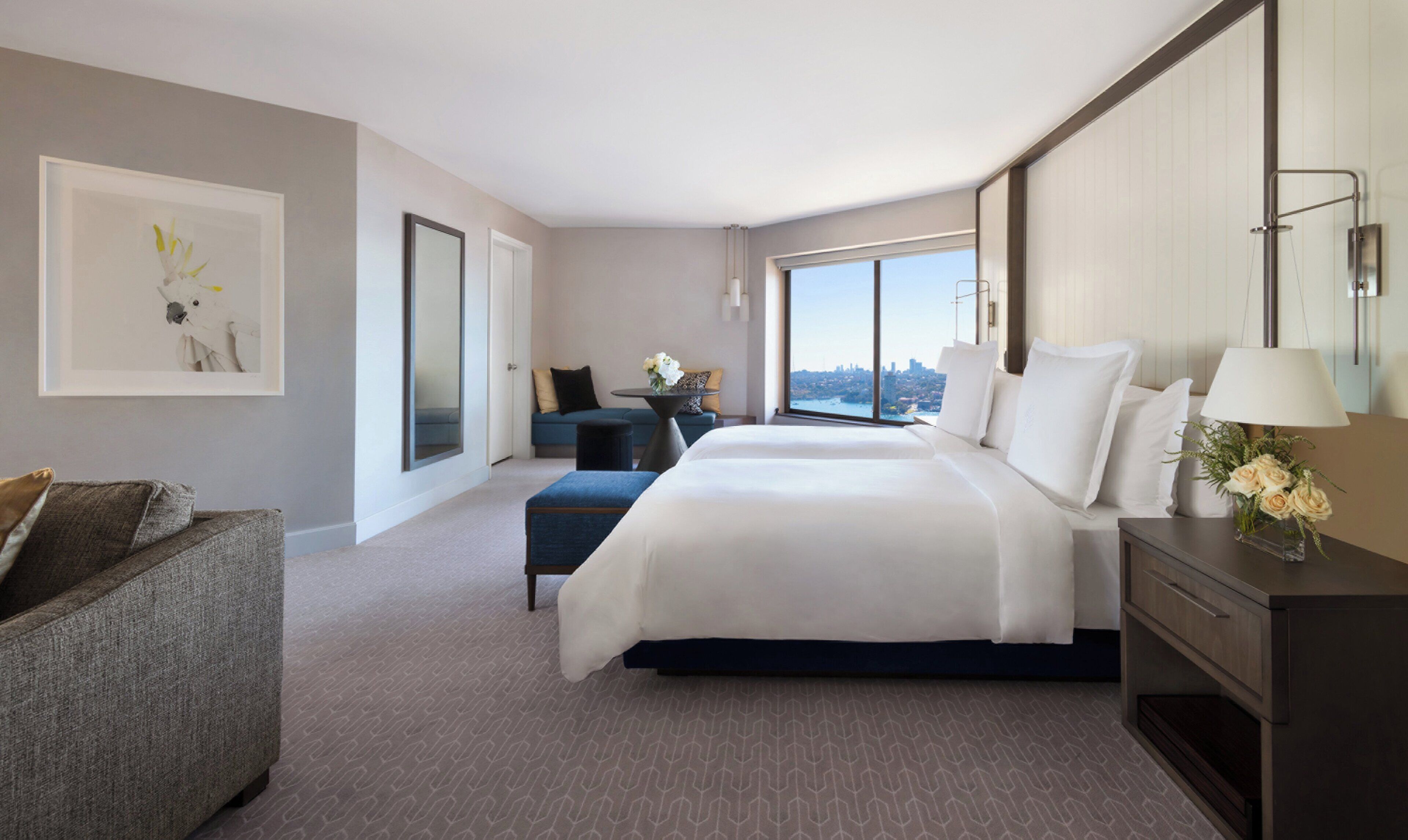 A hotel room with a large bed, a sofa, a desk, and a view of the city.