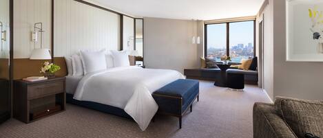 Een moderne hotelkamer met een groot bed, een zithoek met uitzicht en een stadsbeeld door het raam.