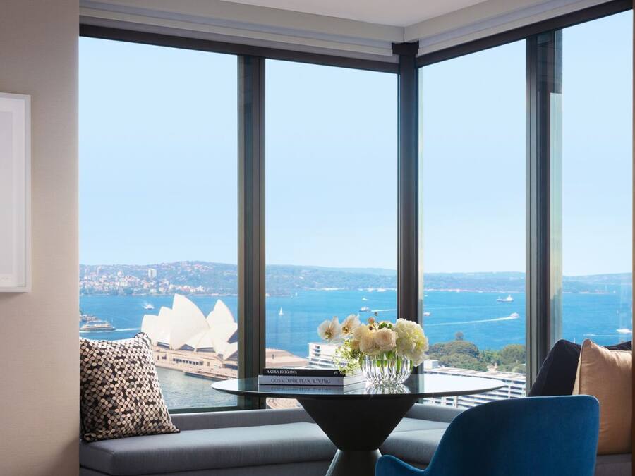 A modern living room with a large window overlooking a cityscape and harbor.