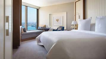 Habitación de hotel con una cama grande, un escritorio con silla, vista a la ciudad y un cuadro en la pared.