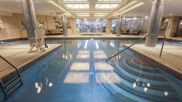 An indoor swimming pool with clear lane markings, a lifeguard chair, and a glass door entrance. - Radisson Plaza Hotel at Kalamazoo Center (Kalamazoo)