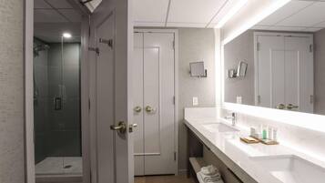 A modern bathroom with a large mirror, a shower, and a vanity with a sink and towel rack.