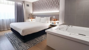 A modern hotel room with a large bed, a separate bathroom with a bathtub, and a patterned wall. - Radisson Plaza Hotel at Kalamazoo Center (Kalamazoo)