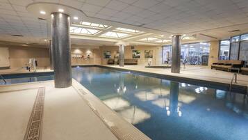 Una piscina interior con agua cristalina, paredes de azulejos y un techo con tragaluces.