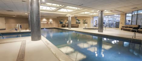 Una piscina interior con agua cristalina, paredes de azulejos y un techo con tragaluces.