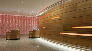 A reception area with a wooden reception desk and a wall with horizontal wooden panels and recessed lighting. - Radisson Plaza Hotel at Kalamazoo Center (Kalamazoo)