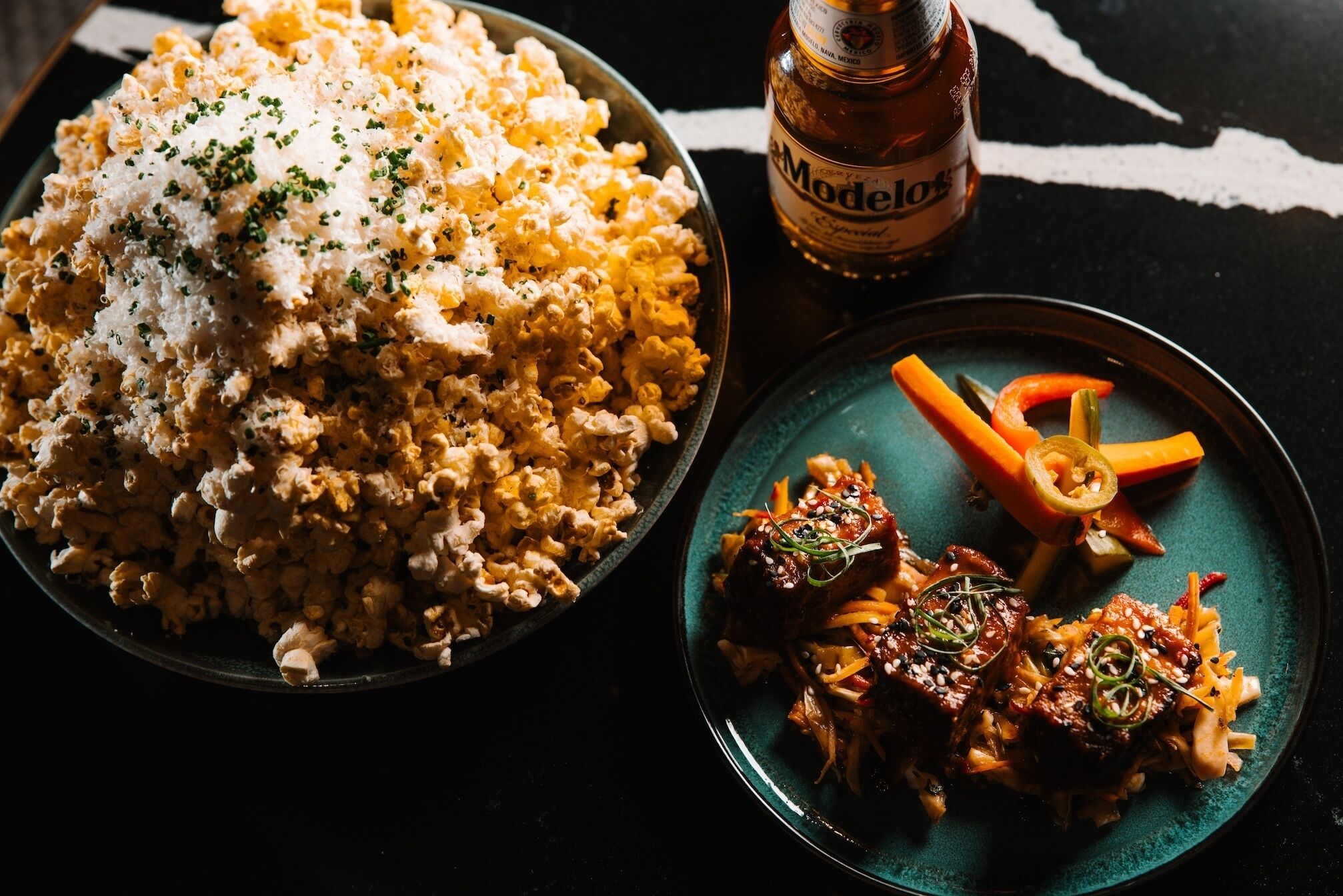 Un plato con arroz, verduras y una botella de cerveza.