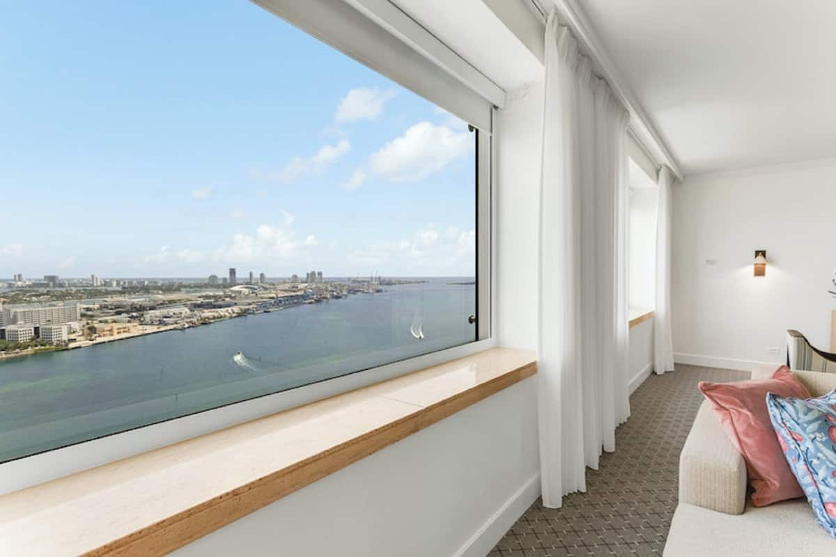 A modern hotel room with a large window overlooking a cityscape and water.