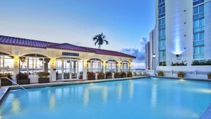 A pool area with a Blue Water Cafe, a palm tree, and a tall building in the background.