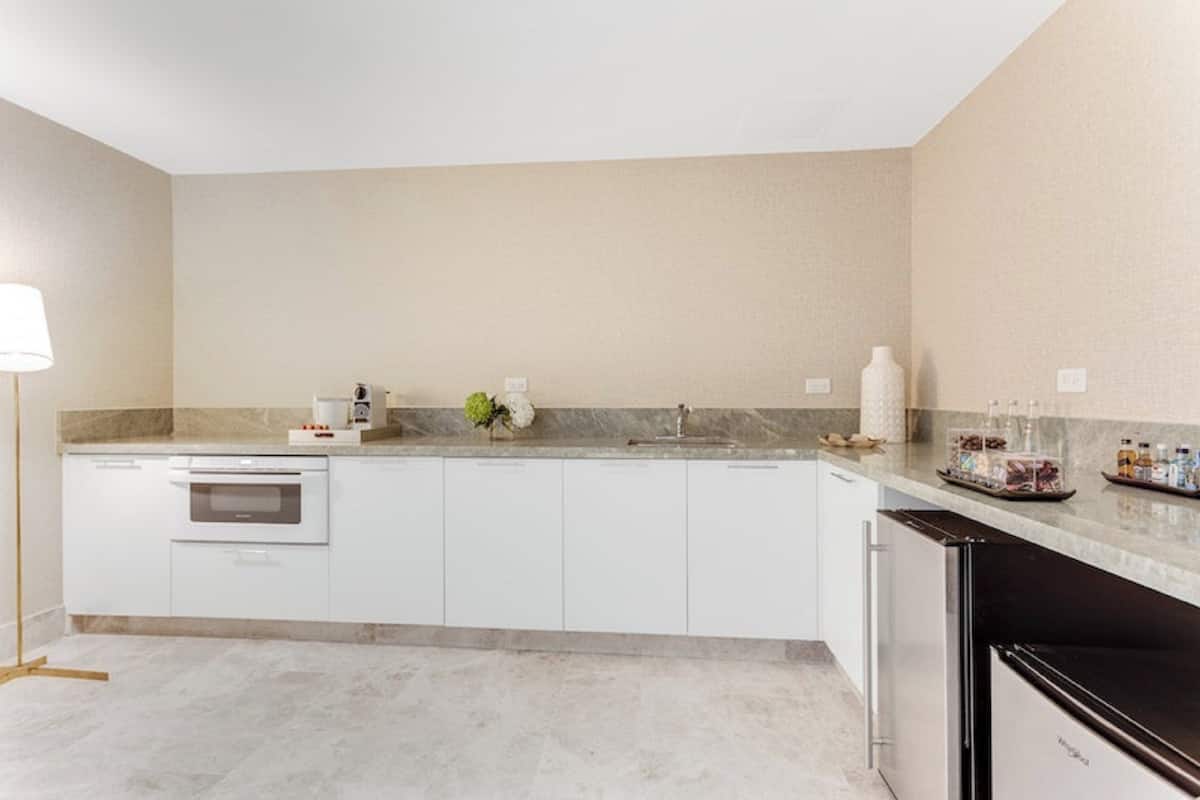 A modern kitchen with white cabinetry, a built-in oven, a sink, and a refrigerator.