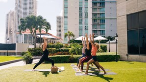 A group of people doing yoga on mats in an outdoor area with a cityscape in the background. - InterContinental Miami by IHG (Miami)