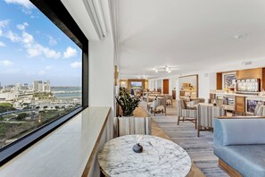 A modern hotel lobby with a city view, a bar area, and seating arrangements.