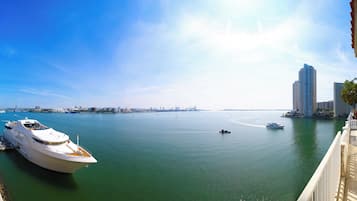 A marina with boats docked, a bridge in the distance, and high-rise buildings along the waterfront.