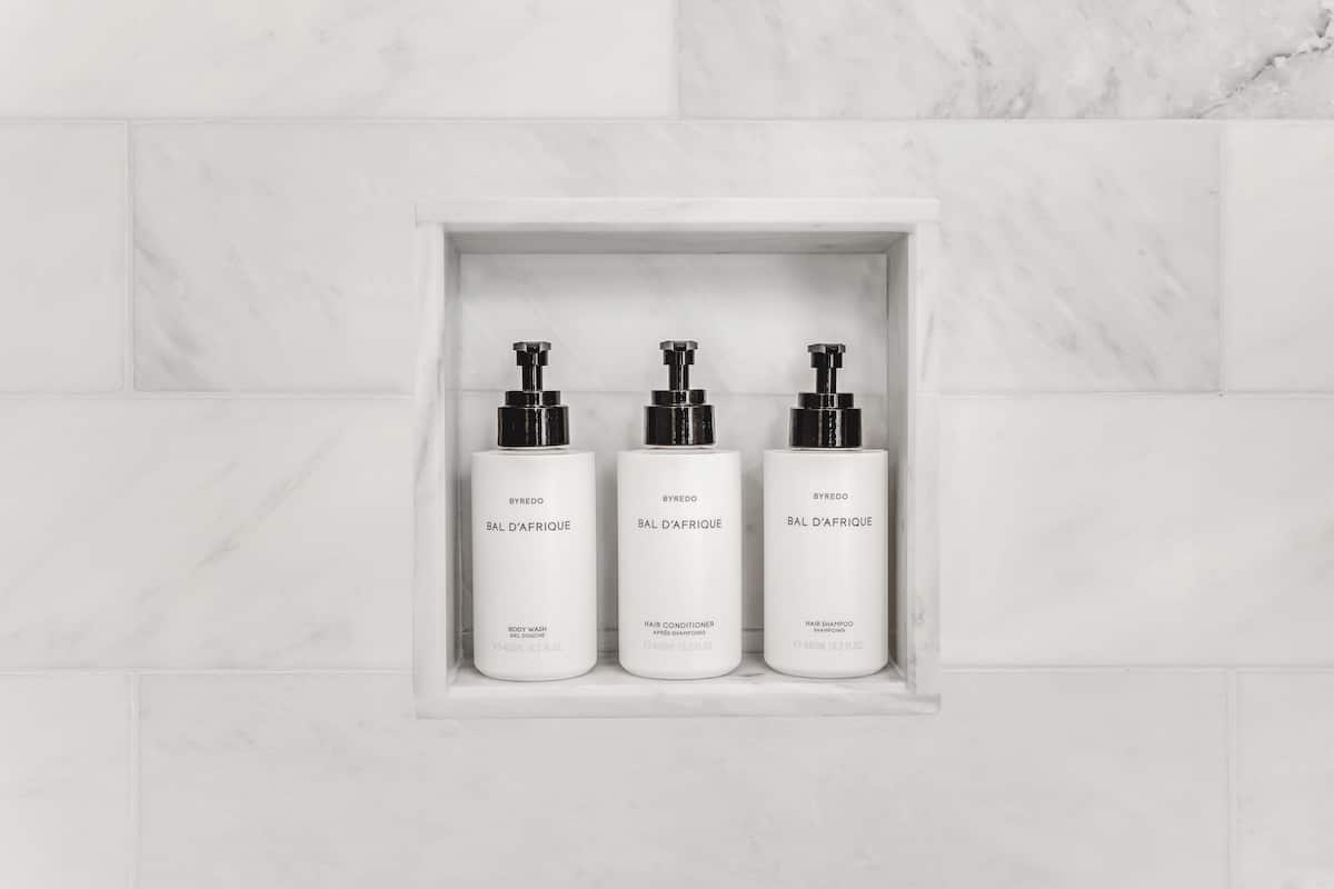 Three white bottles of Byredo Bal d'Afrique products in a white marble shelf.